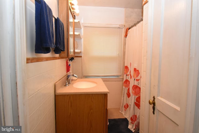 bathroom featuring tile walls and vanity with extensive cabinet space