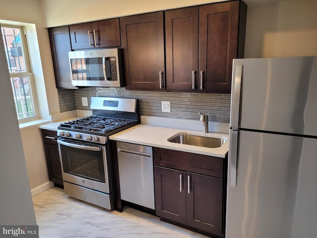 kitchen featuring sink, stainless steel appliances, tasteful backsplash, and dark brown cabinets