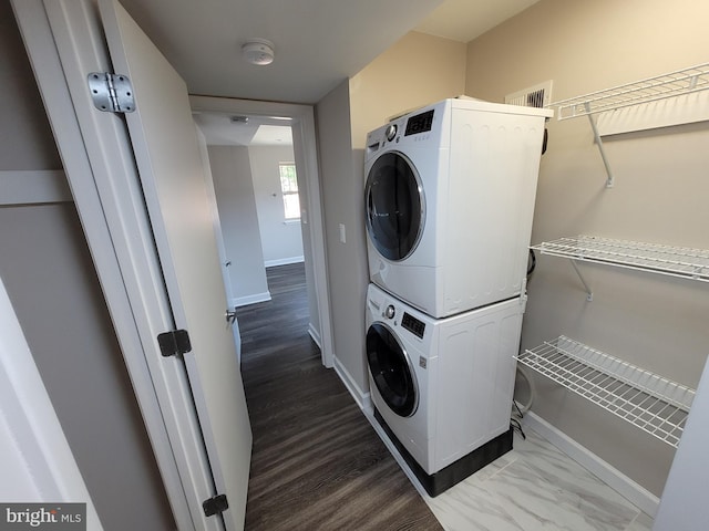 laundry area featuring dark hardwood / wood-style flooring and stacked washer / drying machine