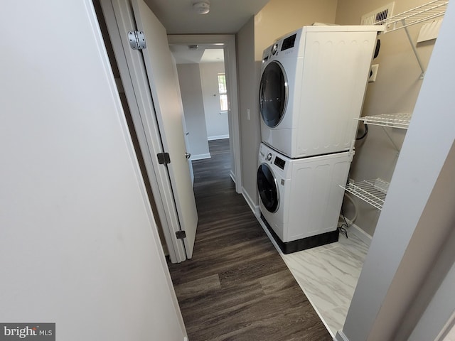 clothes washing area with stacked washer / drying machine and dark wood-type flooring