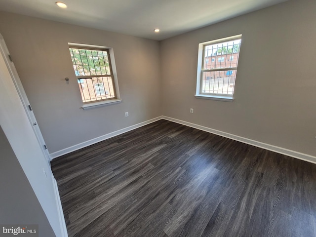 spare room featuring dark wood-type flooring and plenty of natural light