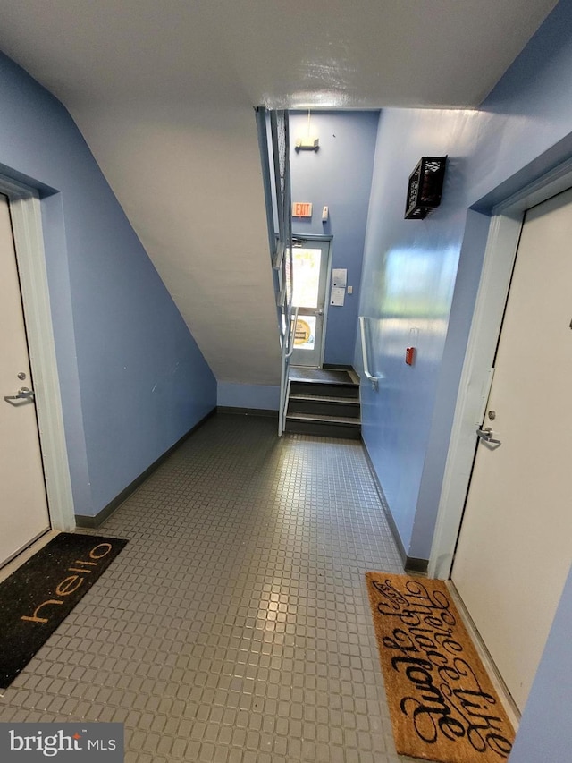 corridor featuring vaulted ceiling and light tile floors