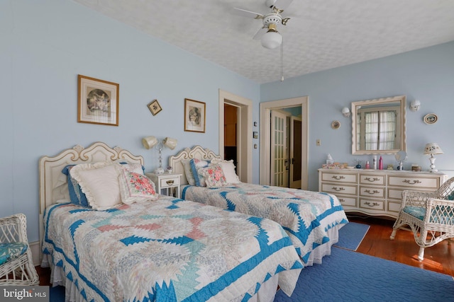 bedroom featuring ceiling fan, dark wood-type flooring, and a textured ceiling