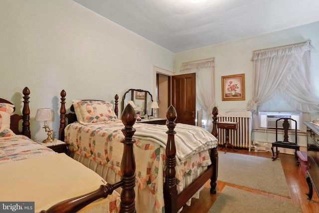 bedroom featuring hardwood / wood-style floors, radiator heating unit, and cooling unit