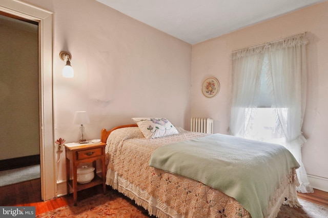 bedroom with wood-type flooring and radiator heating unit