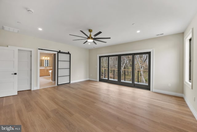 unfurnished bedroom featuring a barn door, visible vents, access to outside, and multiple windows