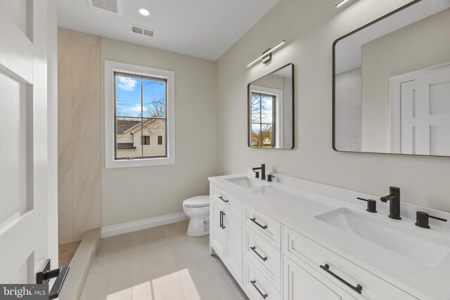 bathroom featuring tile patterned floors, toilet, baseboards, and a sink
