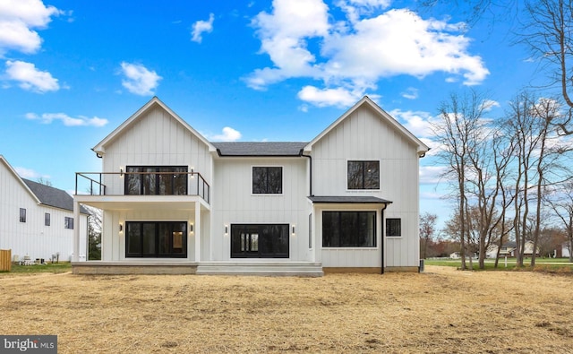 back of property with a balcony and a shingled roof