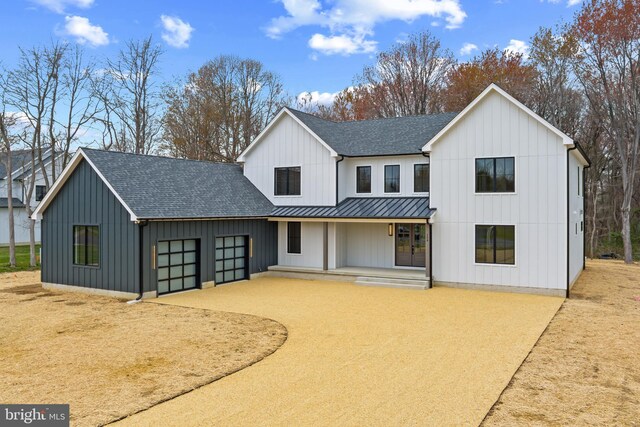 modern inspired farmhouse featuring an attached garage, french doors, board and batten siding, and roof with shingles