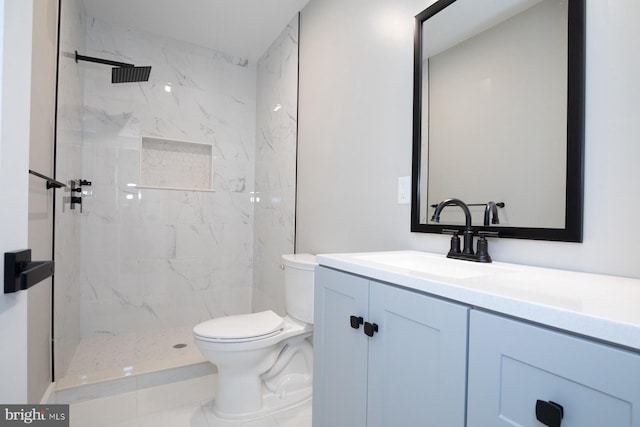 bathroom with vanity, toilet, and tiled shower