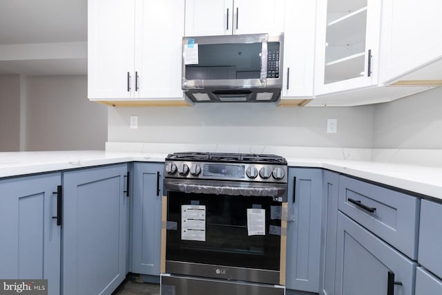 kitchen featuring white cabinets, appliances with stainless steel finishes, and light stone counters