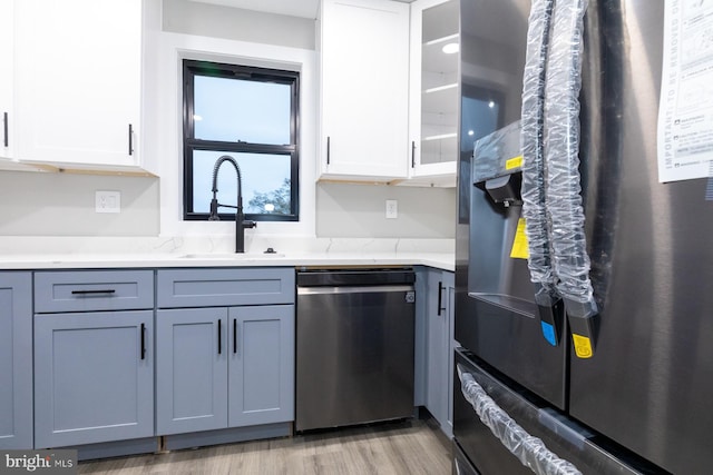 kitchen with white cabinets, refrigerator, light hardwood / wood-style flooring, dishwasher, and sink