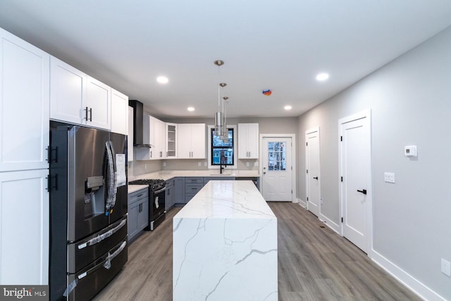 kitchen featuring wall chimney range hood, light hardwood / wood-style flooring, white cabinets, and black appliances