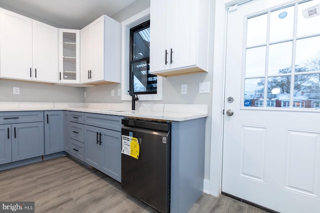 kitchen featuring light stone countertops, light hardwood / wood-style flooring, white cabinetry, gray cabinetry, and dishwasher