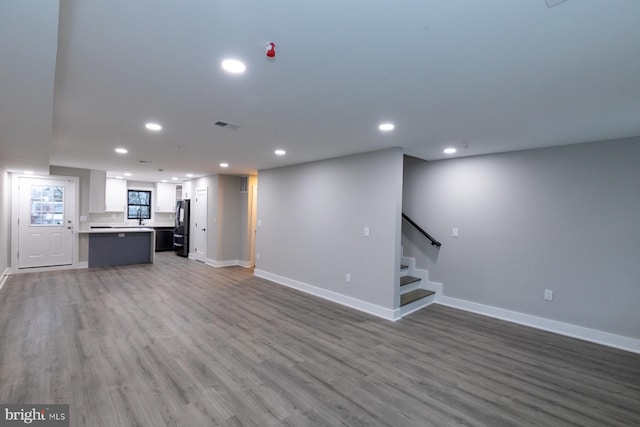 unfurnished living room with hardwood / wood-style floors and sink