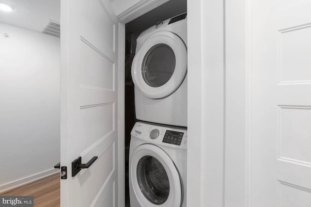 laundry area featuring stacked washing maching and dryer and wood-type flooring