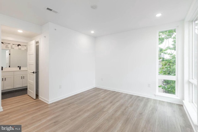 unfurnished bedroom with connected bathroom, track lighting, and light wood-type flooring