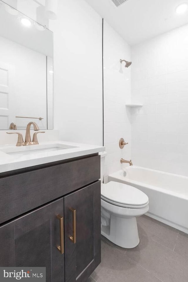 full bathroom with tile floors, tiled shower / bath, toilet, and vanity