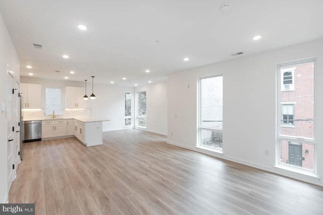 kitchen with plenty of natural light, hanging light fixtures, light hardwood / wood-style flooring, and white cabinetry