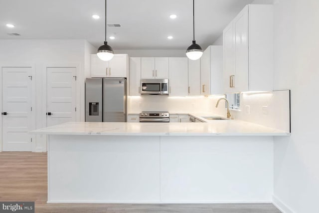 kitchen featuring appliances with stainless steel finishes, tasteful backsplash, light hardwood / wood-style floors, sink, and white cabinets