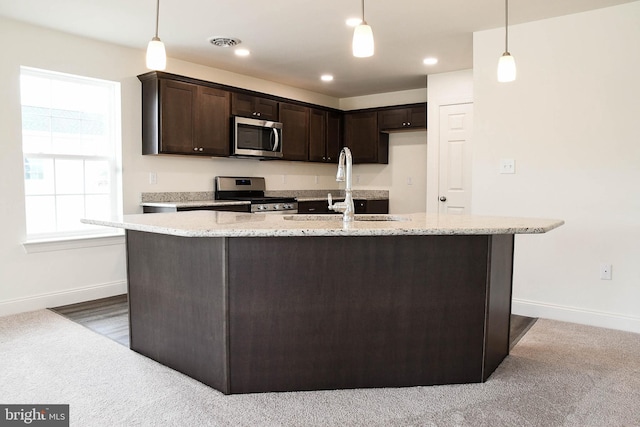 kitchen featuring pendant lighting, sink, light stone counters, carpet, and stainless steel appliances