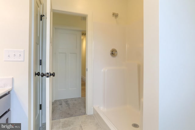 bathroom with a shower, tile floors, and vanity