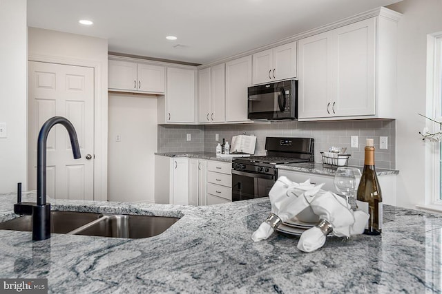 kitchen with white cabinets, gas range oven, backsplash, and light stone counters