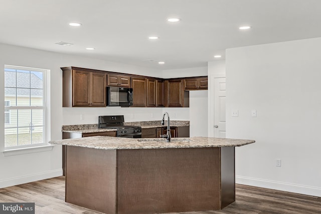 kitchen featuring an island with sink, gas range, dark brown cabinets, light hardwood / wood-style flooring, and sink