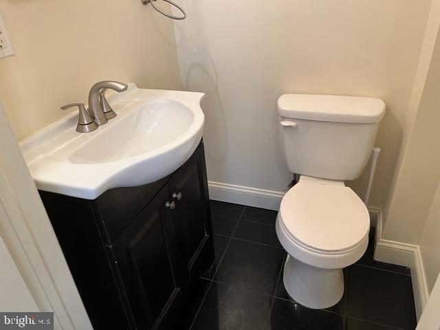 bathroom featuring toilet, tile flooring, and vanity