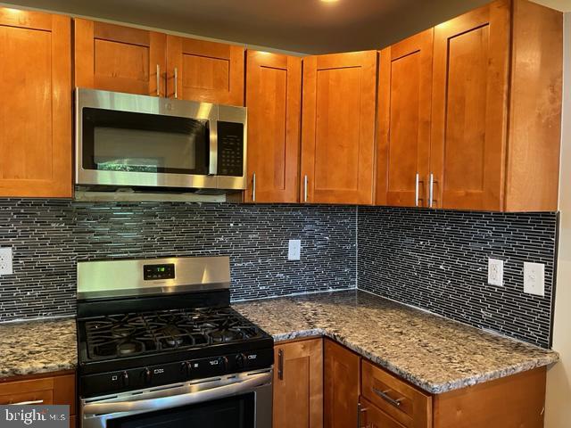 kitchen with tasteful backsplash, stainless steel appliances, and light stone countertops