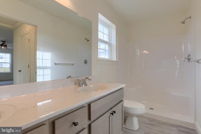 bathroom with ceiling fan, toilet, walk in shower, and vanity