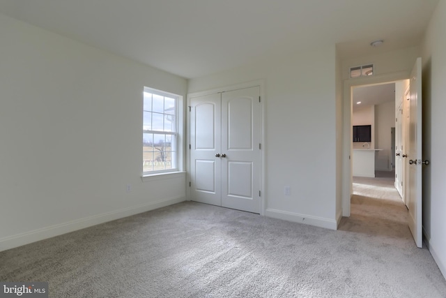 unfurnished bedroom with a closet and light colored carpet