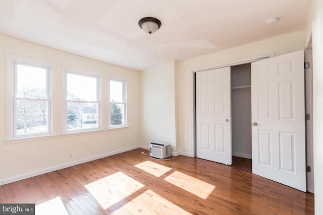 unfurnished bedroom with a closet, multiple windows, and dark hardwood / wood-style floors