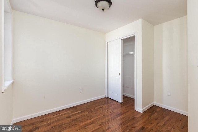 unfurnished bedroom with a closet and dark wood-type flooring