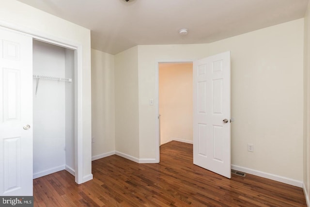 unfurnished bedroom featuring a closet and dark wood-type flooring