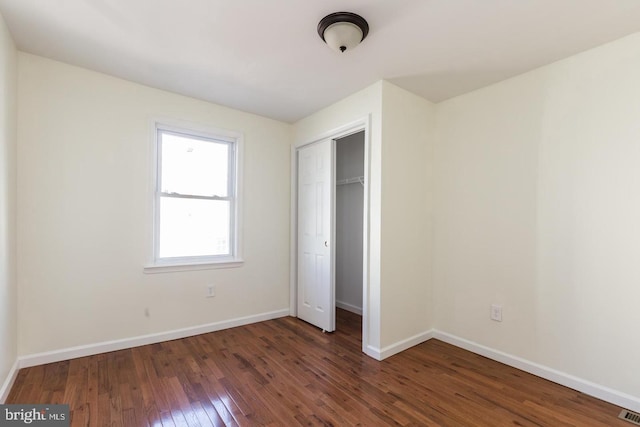 unfurnished bedroom featuring dark hardwood / wood-style flooring and a closet