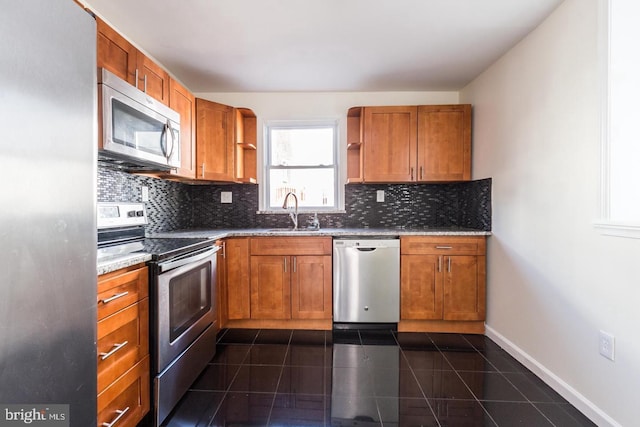 kitchen with stainless steel appliances, dark stone counters, tasteful backsplash, dark tile flooring, and sink