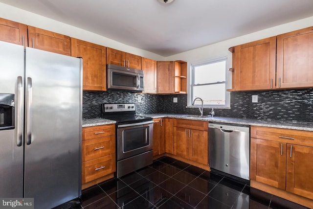 kitchen with backsplash, light stone countertops, appliances with stainless steel finishes, and dark tile flooring