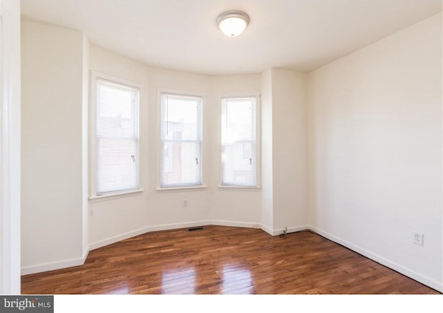 spare room featuring dark hardwood / wood-style floors and plenty of natural light