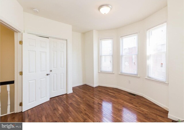 unfurnished bedroom with dark hardwood / wood-style floors and a closet