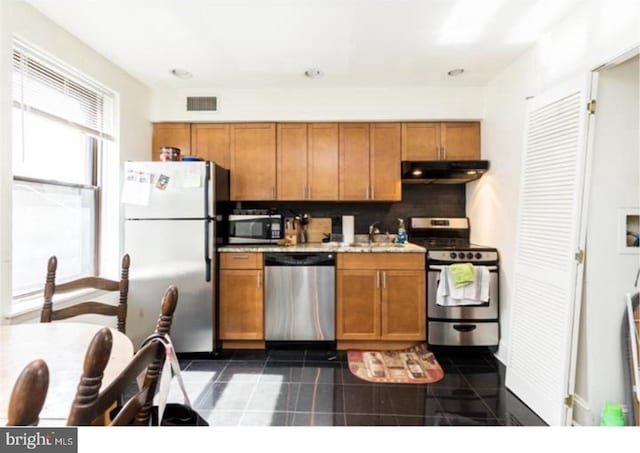 kitchen featuring dark tile flooring, sink, tasteful backsplash, and stainless steel appliances