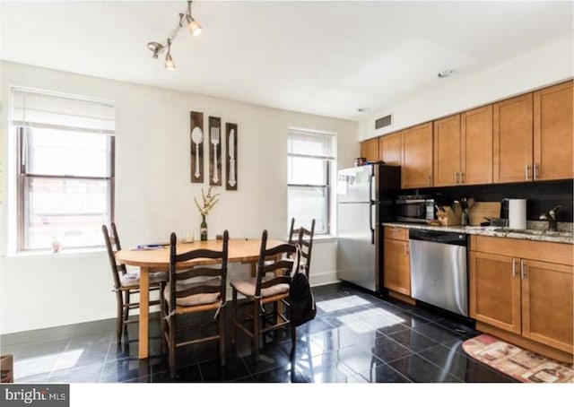 kitchen featuring light stone countertops, sink, stainless steel appliances, and dark tile floors