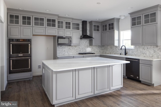 kitchen with a center island, gray cabinetry, glass insert cabinets, wall chimney range hood, and black appliances