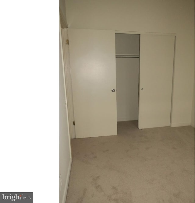 unfurnished bedroom featuring a closet and light colored carpet