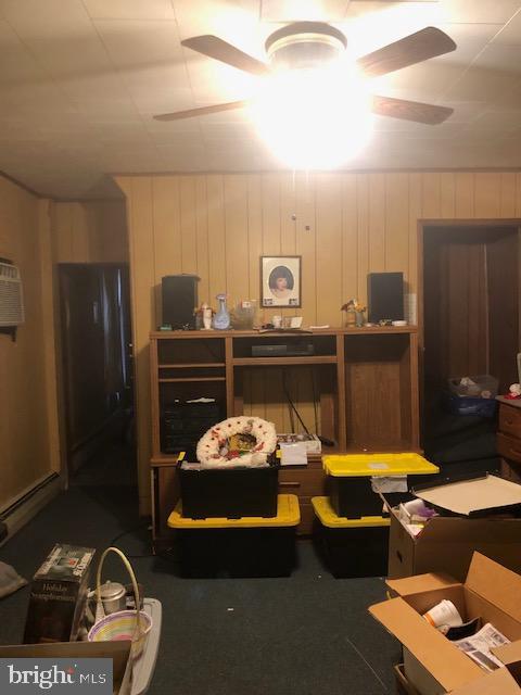 interior space with ceiling fan, a baseboard heating unit, and a wall unit AC