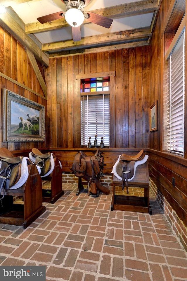 sitting room with a wealth of natural light, wooden walls, and ceiling fan