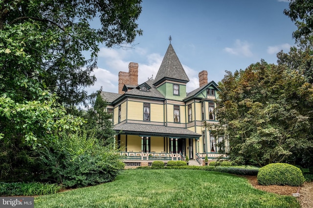 rear view of property featuring a porch and a yard