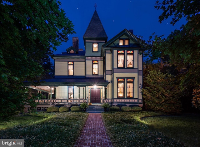 victorian-style house featuring a lawn and a porch