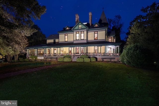 back house at twilight featuring a lawn