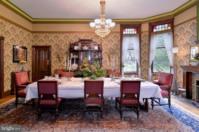 dining area featuring a fireplace, ornamental molding, and an inviting chandelier